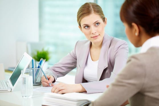 Two women sitting at a table, having a meeting.
