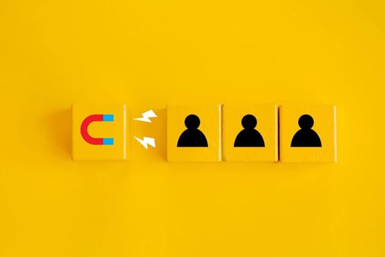 Magnet block attracting person blocks, in a yellow background.