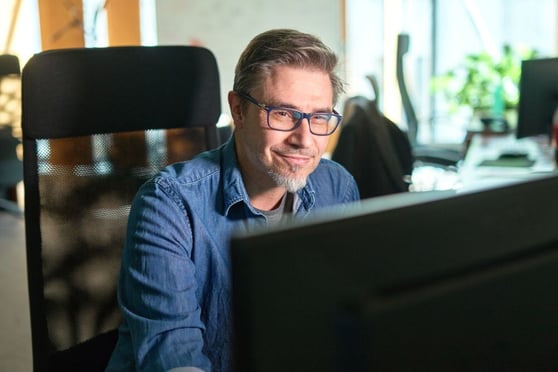 Man smiling at his computer screen.