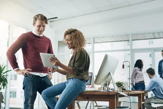 Two people reviewing a tablet, in an office environment.