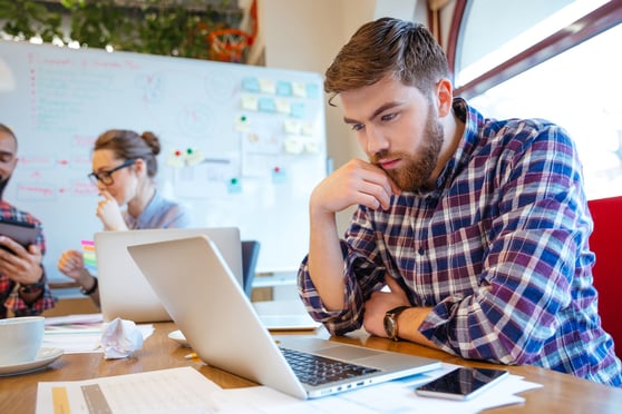 Concentrated bearded man using laptop