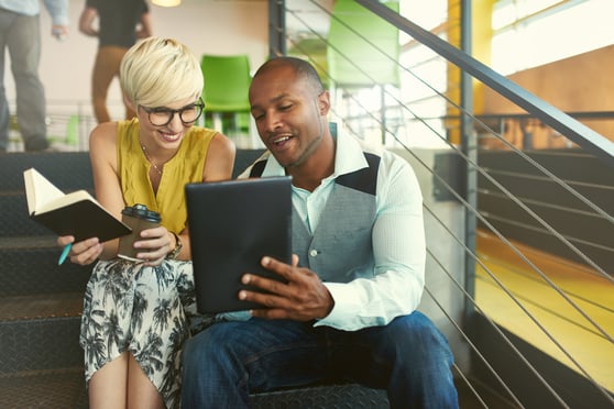 Dos creativos milenials trabajando en una estrategia de social media en una escalera