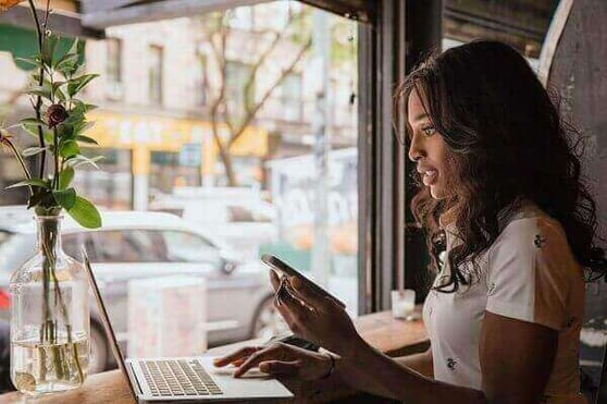 Woman sitting by a window with a laptop.