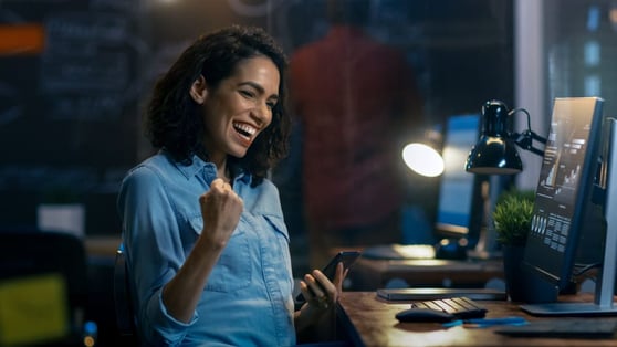 Woman celebrating in front of a computer screen.