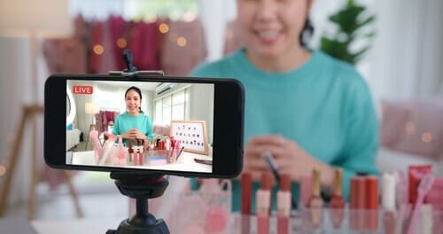 Person on the foreground of a cell phone screen, on video in the background.