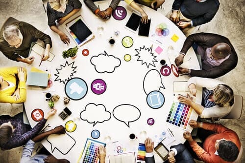 People sitting around a white table, with social icons on the table.