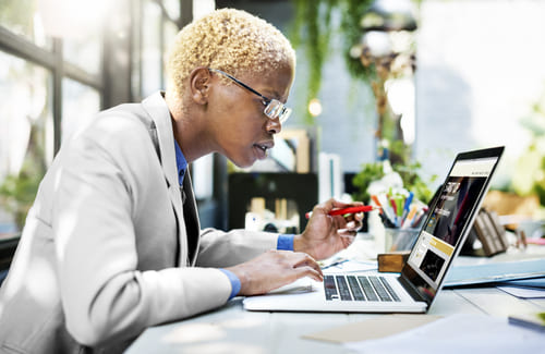 Woman sitting at a table with an open laptop.