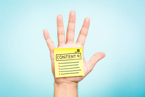 Open hand with a yellow sticky note on it that says content.