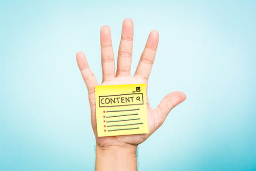 Open hand with a yellow sticky note on it that says content.