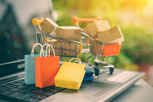 Small shopping carts with shopping boxes on top of an open laptop keyboard.