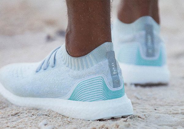 Image of person wearing blue and grey shoes on beach.