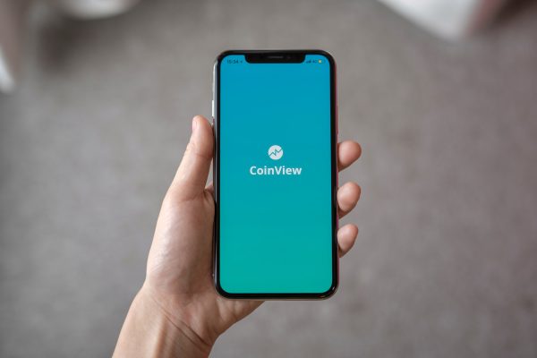 Hand holding a phone with the CoinView app open on the screen.